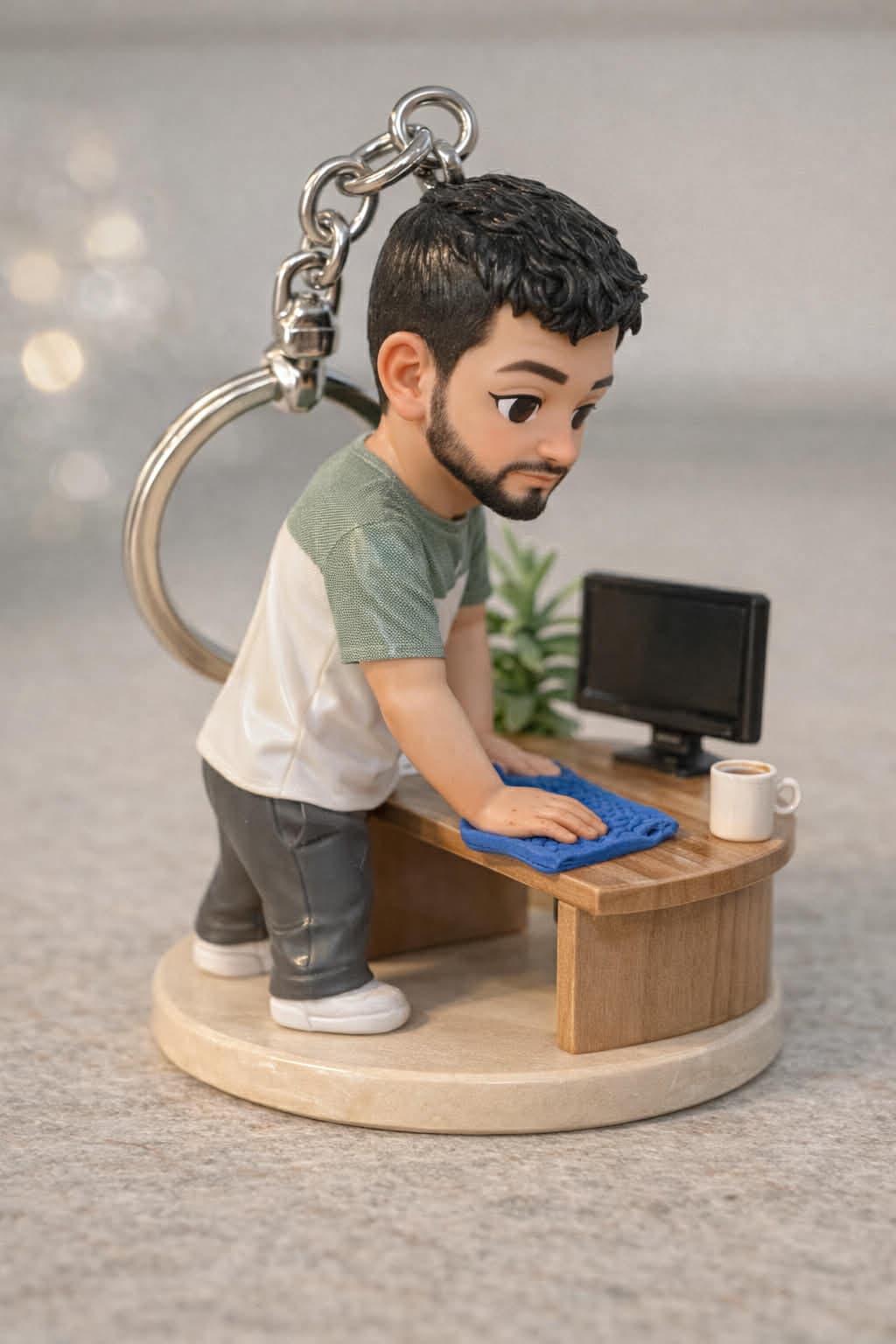 Miniature keychain figurine of a bearded man cleaning a desk with a monitor and mug.